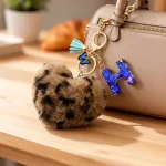 Personalized brown plush heart keychain with blue acrylic initial for backpack