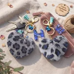 Personalized grey plush heart keychain with blue acrylic initial for backpack