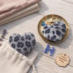 Personalized grey plush heart keychain with blue acrylic initial for backpack