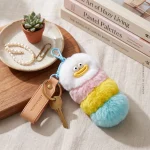Close-up of fluffy worm monster keychain showing hand-stitched smiley face and soft faux fur texture.