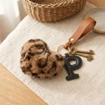 Close-up of the leather initial keychain showing leopard faux fur heart and stitched genuine leather letter.