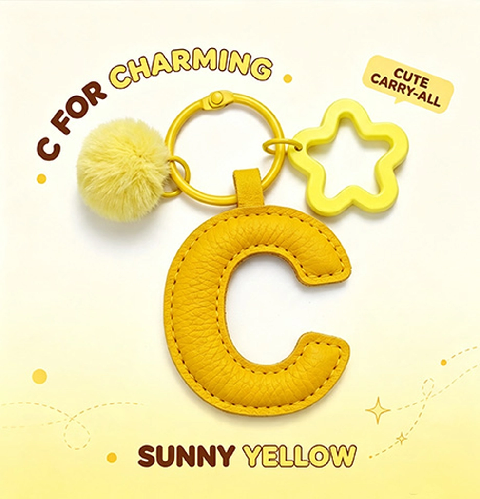 Close-up of the Letter C keychain showing padded sunny yellow PU leather and soft faux fur pom pom.