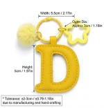 Close-up of the Letter D keychain showing padded sunny yellow PU leather and soft faux fur pom pom.