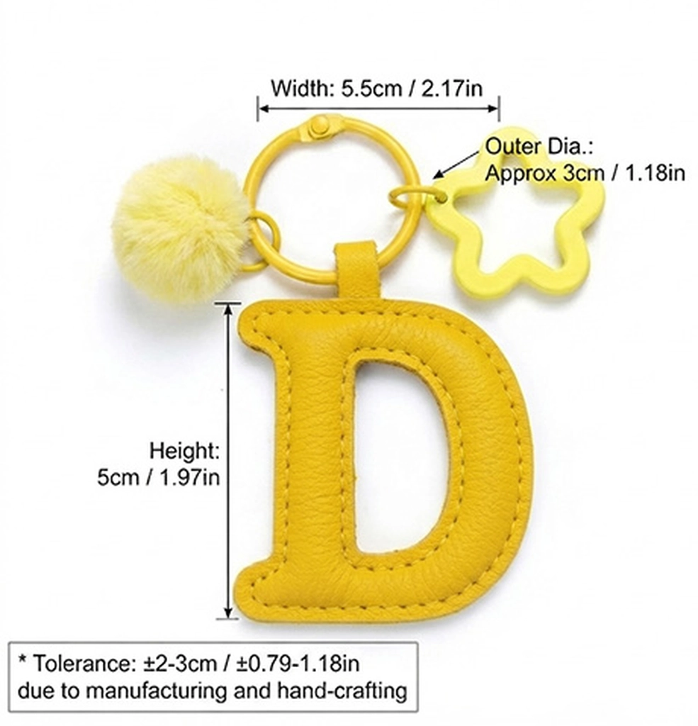 Close-up of the Letter D keychain showing padded sunny yellow PU leather and soft faux fur pom pom.