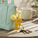 Close-up of the Letter F keychain showing padded sunny yellow PU leather and soft faux fur pom pom.