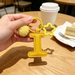 Close-up of the Letter I keychain showing padded sunshine yellow PU leather and soft faux fur pom pom.