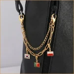 Close-up of the travel flag charm showing glossy epoxy resin surface and gold plated edge.