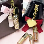 Gold Lip Gloss Bag Charm with Satin Bow and Heart Mirror, Portable Lipstick Cage Keychain Gift