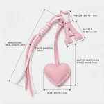 Personalized initial heart bag charm in pink PU leather with letter A and braided tassel on book flat lay